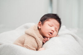 Na zdjęciu widoczne jest urocze niemowlę, które śpi spokojnie w przytulnym ubranku. Ubranie jest wykonane z miękkiego i delikatnego materiału, co zapewnia maluszkowi wygodę i ciepło. Taki obrazek może przypominać każdemu, jak ważne jest, aby zadbać o wygodę i komfort dziecka, szczególnie w pierwszych miesiącach życia, kiedy potrzebuje ono dużo snu i odpoczynku.