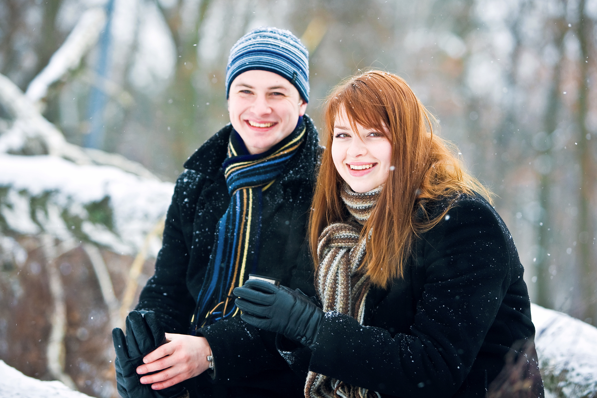 Na tym zdjęciu widzimy parę w wieku 14 lat, która spaceruje w zimowej scenerii. Chłopak trzyma dziewczynę za rękę, a ona ma na sobie ciepłą kurtkę z futrzanym kapturem. W tle widać śnieżne drzewa i biały krajobraz. Para uśmiecha się do siebie i wydaje się, że dobrze się bawią, chociaż jest zimno. Całość tworzy romantyczną i spokojną atmosferę, która idealnie wpisuje się w zimową aurę.