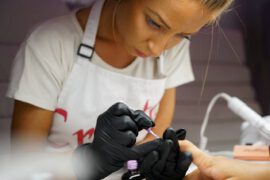 Kobieta podczas robienia paznokci klientce