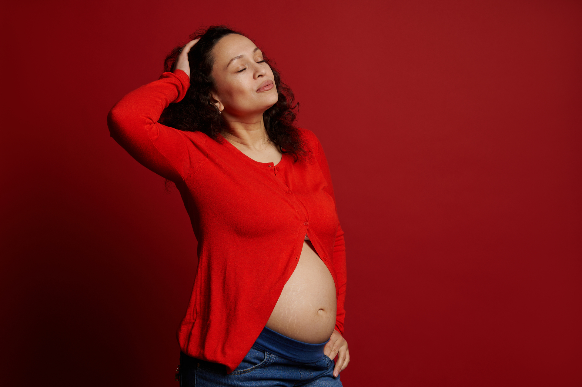 Na tym obrazku widzimy kobietę w ciąży, która jest przedstawiona na intensywnie czerwonym tle, symbolizującym siłę, pasję i determinację. Ta wizualizacja podkreśla zarówno radość, jak i wyzwania związane z byciem matką w trakcie ciąży. Obrazek ten ma na celu odkrycie różnorodnych emocji, jakie towarzyszą temu szczególnemu okresowi życia, oraz podkreślenie piękna i wyjątkowości macierzyństwa