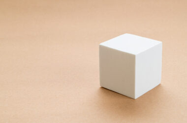 Ten minimalistyczny obrazek przedstawia białą kostkę, która jest w rzeczywistości sześcianem. Prosta forma sześcianu została przedstawiona w czystym, eleganckim stylu, podkreślając jego geometryczną perfekcję. Obrazek emanuje równowagą i prostotą, ukazując piękno i estetykę, które mogą płynąć z podstawowych kształtów geometrycznych