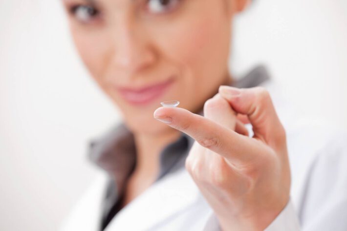Kobieta trzyma na palcu soczewkę kontaktową