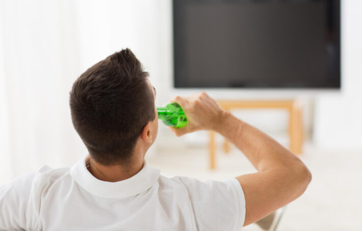 Mężczyzna pije alkohol przed TV