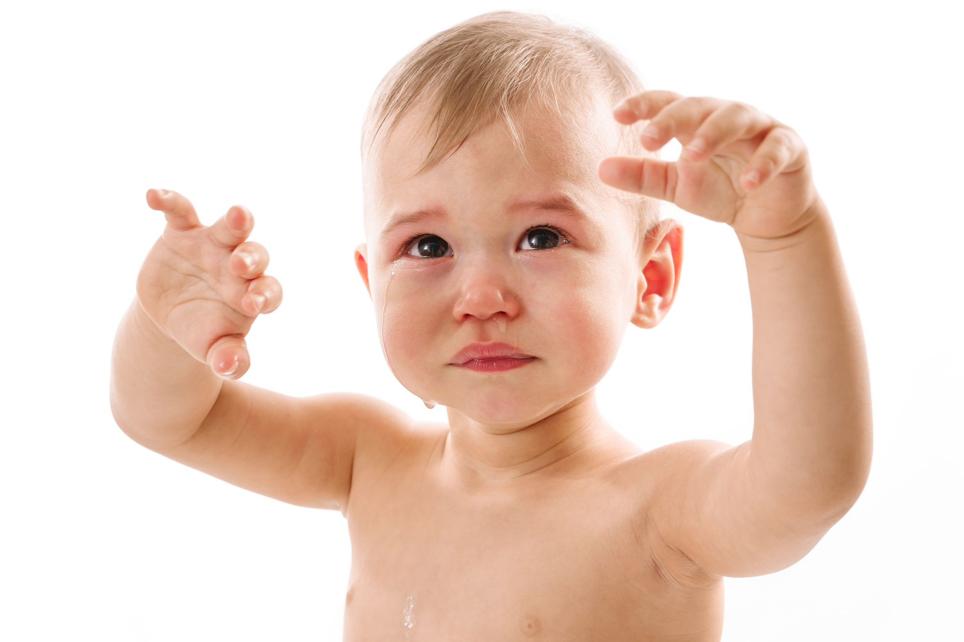 Na obrazku widać niemowlaka, którego delikatna skóra pod pachami jest dotknięta odparzeniami, co powoduje mu dyskomfort i łzy w oczach. Jego małe, smutne oczy odzwierciedlają ból i frustrację, jakie odczuwa. W tle widać opiekuna, który starannie stara się złagodzić dolegliwości malucha, szukając odpowiednich środków pielęgnacyjnych i pocieszając go