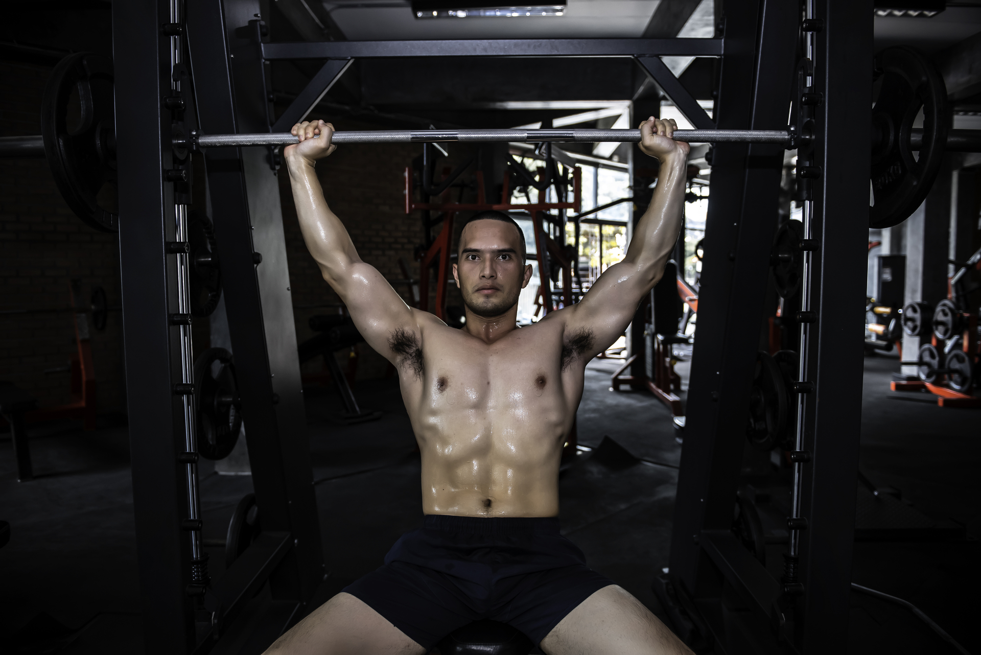 Mężczyzna na siłowni podnoszący sztangę, wykonując trening Arnolda Schwarzeneggera
