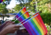 Tęczowe flagi społeczności LGBTQ+ trzymane w dłoniach