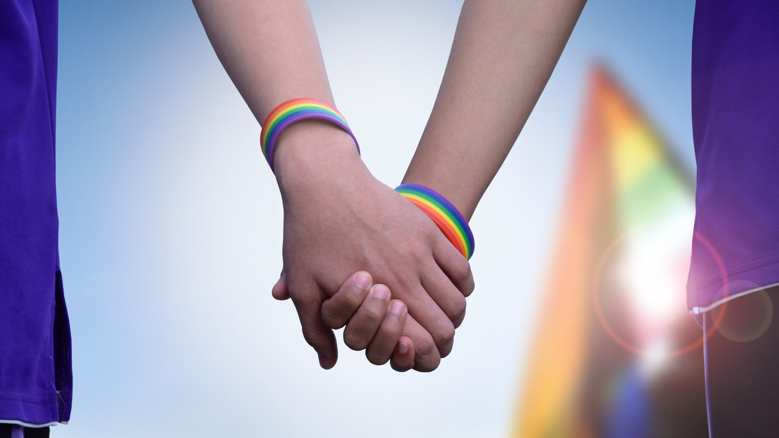 Para homoseksualna trzymająca się za ręce z tęczowymi opaskami